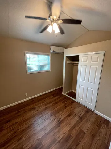 a view of an empty room with wooden floor and a ceiling fan
