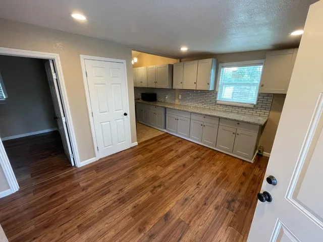 a large kitchen with a refrigerator a window and wooden floor