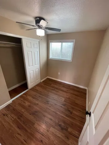 a view of empty room with wooden floor and fan