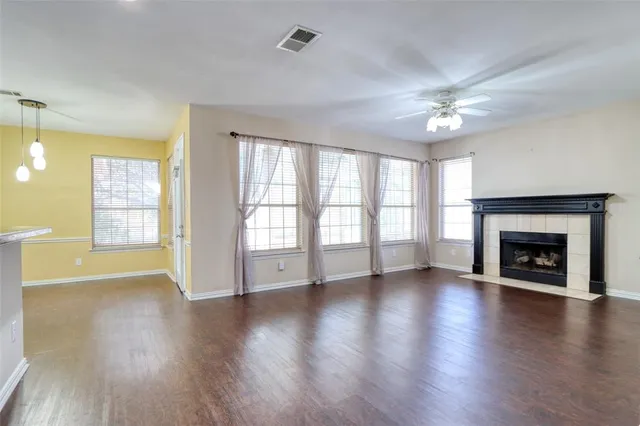 an empty room with wooden floor fireplace and windows