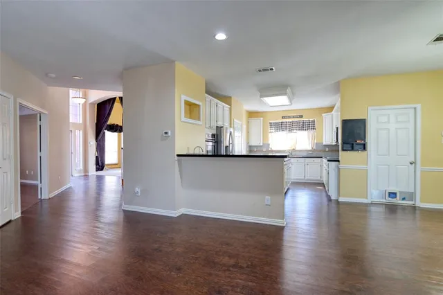 a view of a big room with kitchen view and wooden floor