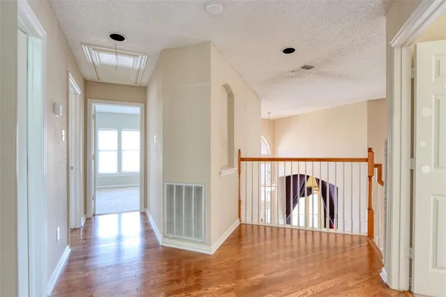 a view of a hallway with wooden floor and windows