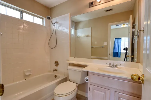 a bathroom with a granite countertop sink a toilet a mirror a bathtub and shower