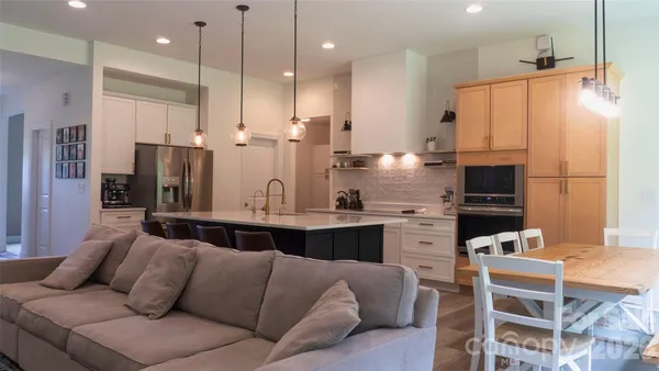 a kitchen with stainless steel appliances kitchen island granite countertop a refrigerator a stove a oven a sink and a dining table with white cabinets