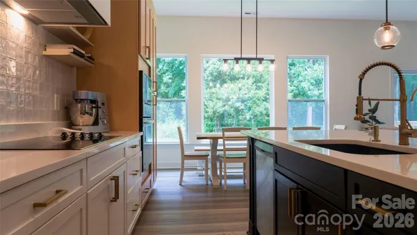 a kitchen with stainless steel appliances granite countertop a sink a stove and a wooden floors