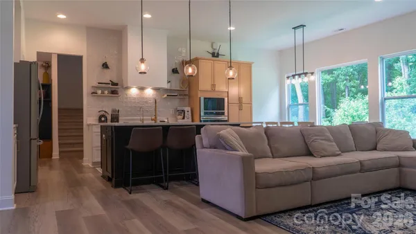 a living room with furniture a large window and kitchen view