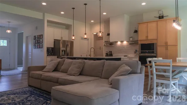 a living room with stainless steel appliances kitchen island granite countertop a couch and a fireplace