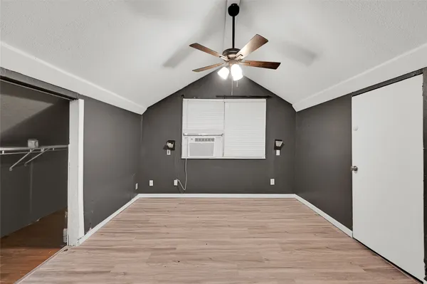 a view of an empty room with a ceiling fan and wooden floor
