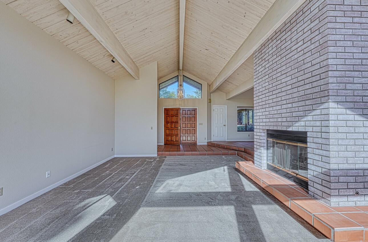 1056 Rodeo Road Pebble Beach, CA 93953 - Photo 6 of 17 a view of an empty room with wooden floor fireplace and a window