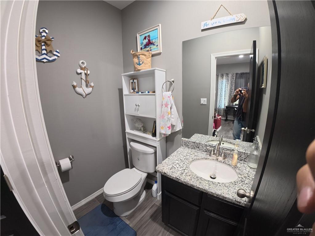 321 Gladiola Drive Edcouch, TX 78538 - Photo 19 of 29 a bathroom with a granite countertop sink a toilet a mirror and shower curtain