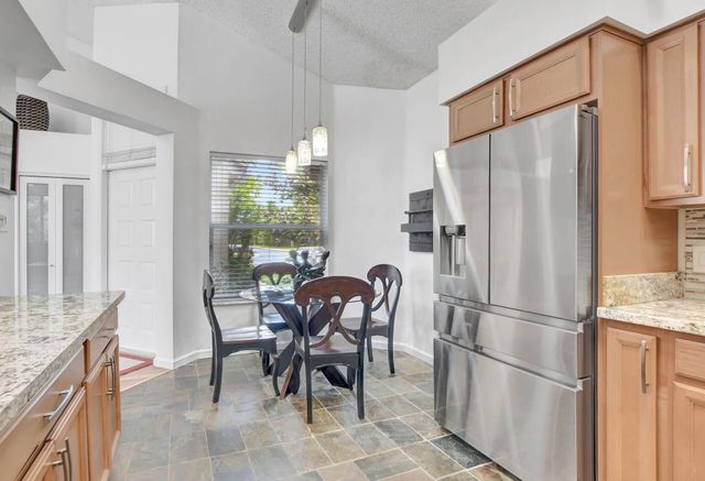 a kitchen with stainless steel appliances granite countertop a refrigerator and a table chair