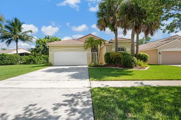 a front view of a house with a garden and palm tree