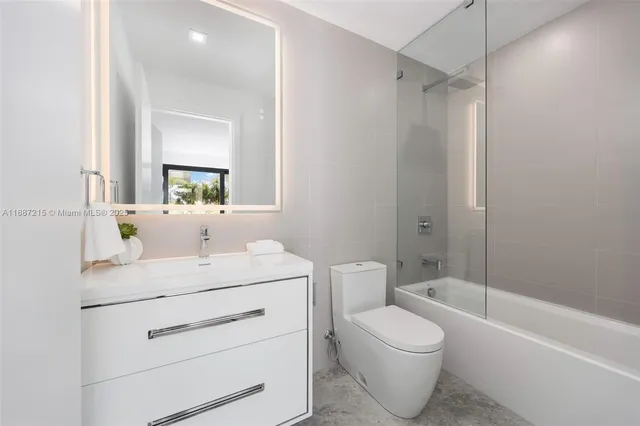 a bathroom with a toilet sink vanity tub and mirror