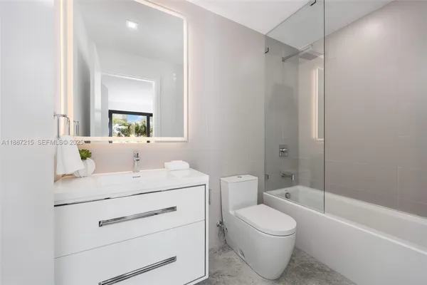 a bathroom with a toilet sink vanity tub and mirror