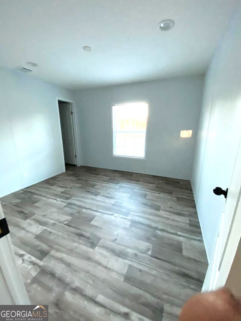 519 Wilson Road Twin City, GA 30471 - Photo 11 of 20 an empty room with wooden floor and windows