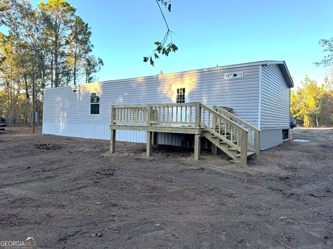 519 Wilson Road Twin City, GA 30471 - Photo 14 of 20 a view of a house with a wooden deck and a yard