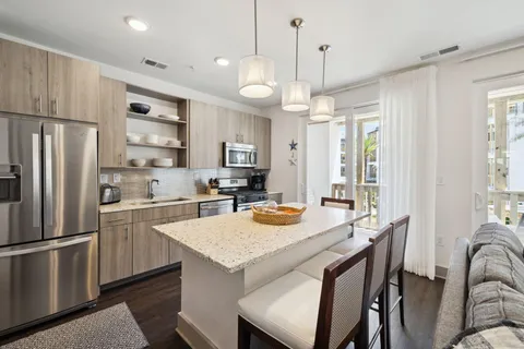 a kitchen with granite countertop a refrigerator a sink a stove a dining table and chairs