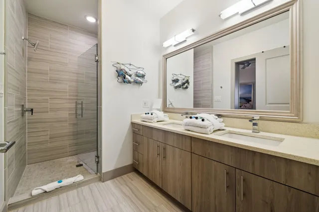 a bathroom with a double vanity sink mirror and shower