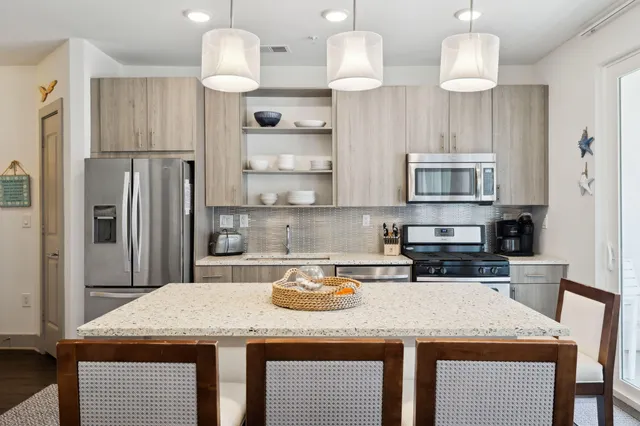 a kitchen with kitchen island granite countertop a sink a center island and stainless steel appliances