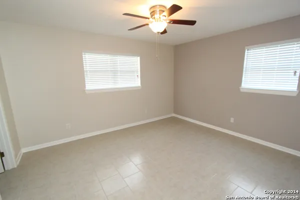 an empty room with a window and a fan