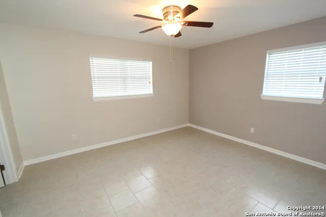 an empty room with a window and a fan