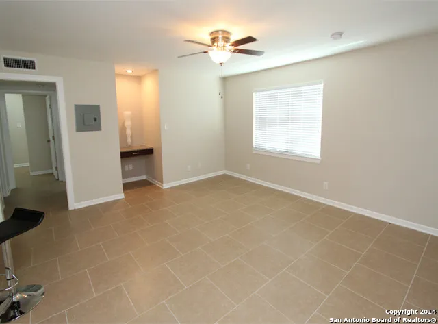 an empty room with chandelier fan and windows