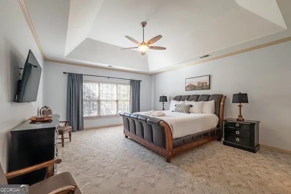 a spacious bedroom with a bed and a flat tv screen on the dresser
