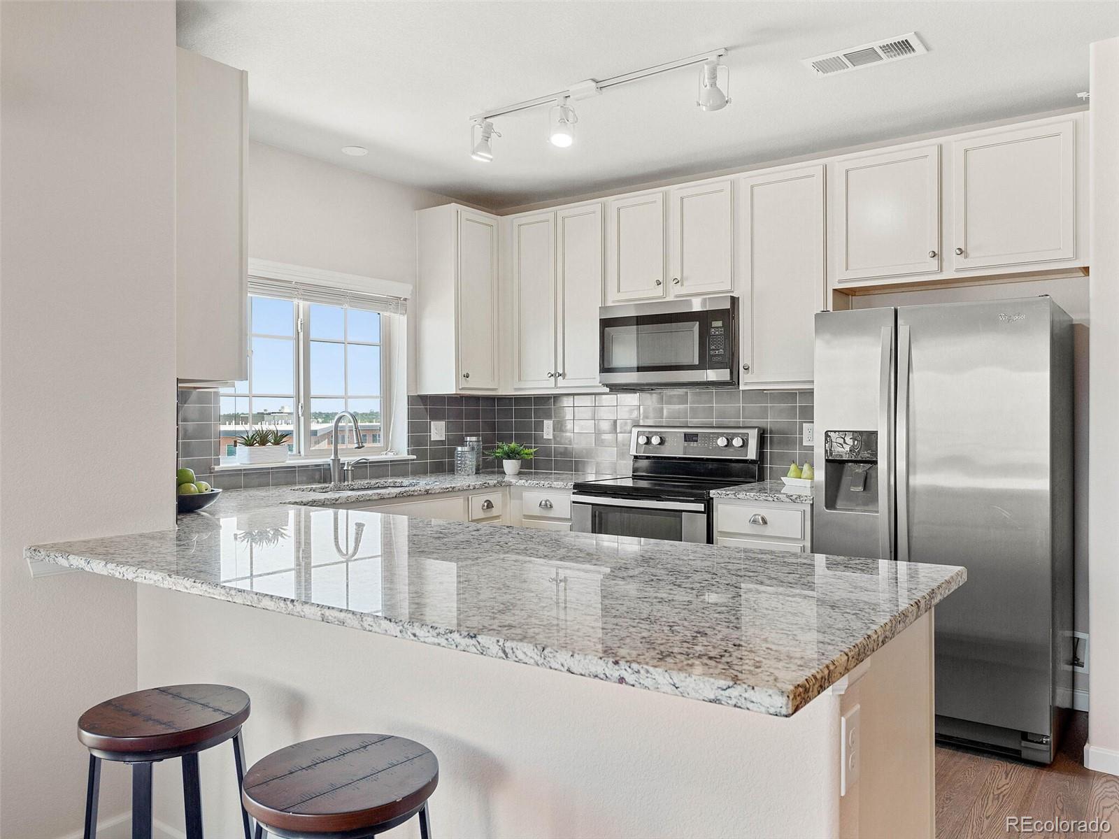 9258 Rockhurst Street, Unit 405 Highlands Ranch, CO 80129 - Photo 13 of 32 a kitchen with stainless steel appliances granite countertop a refrigerator a stove a sink a stove and white cabinets