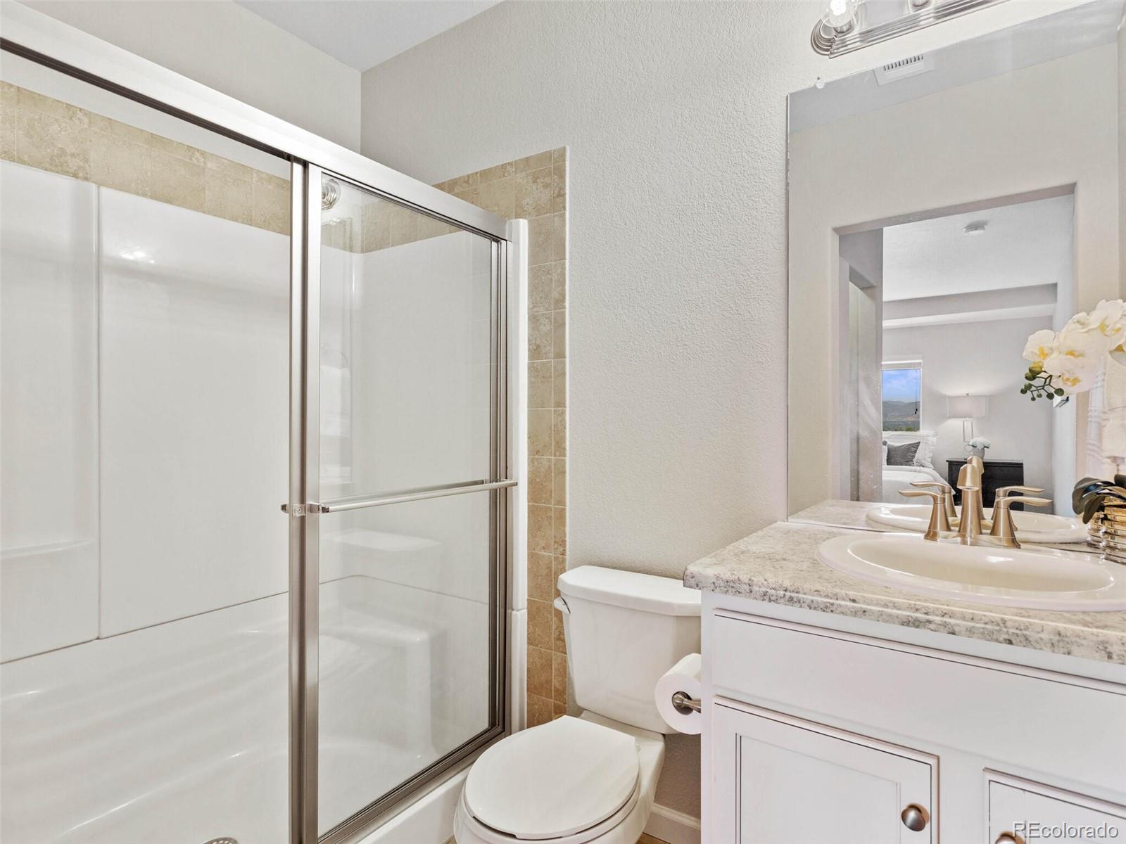 9258 Rockhurst Street, Unit 405 Highlands Ranch, CO 80129 - Photo 20 of 32 a bathroom with a granite countertop sink toilet and shower