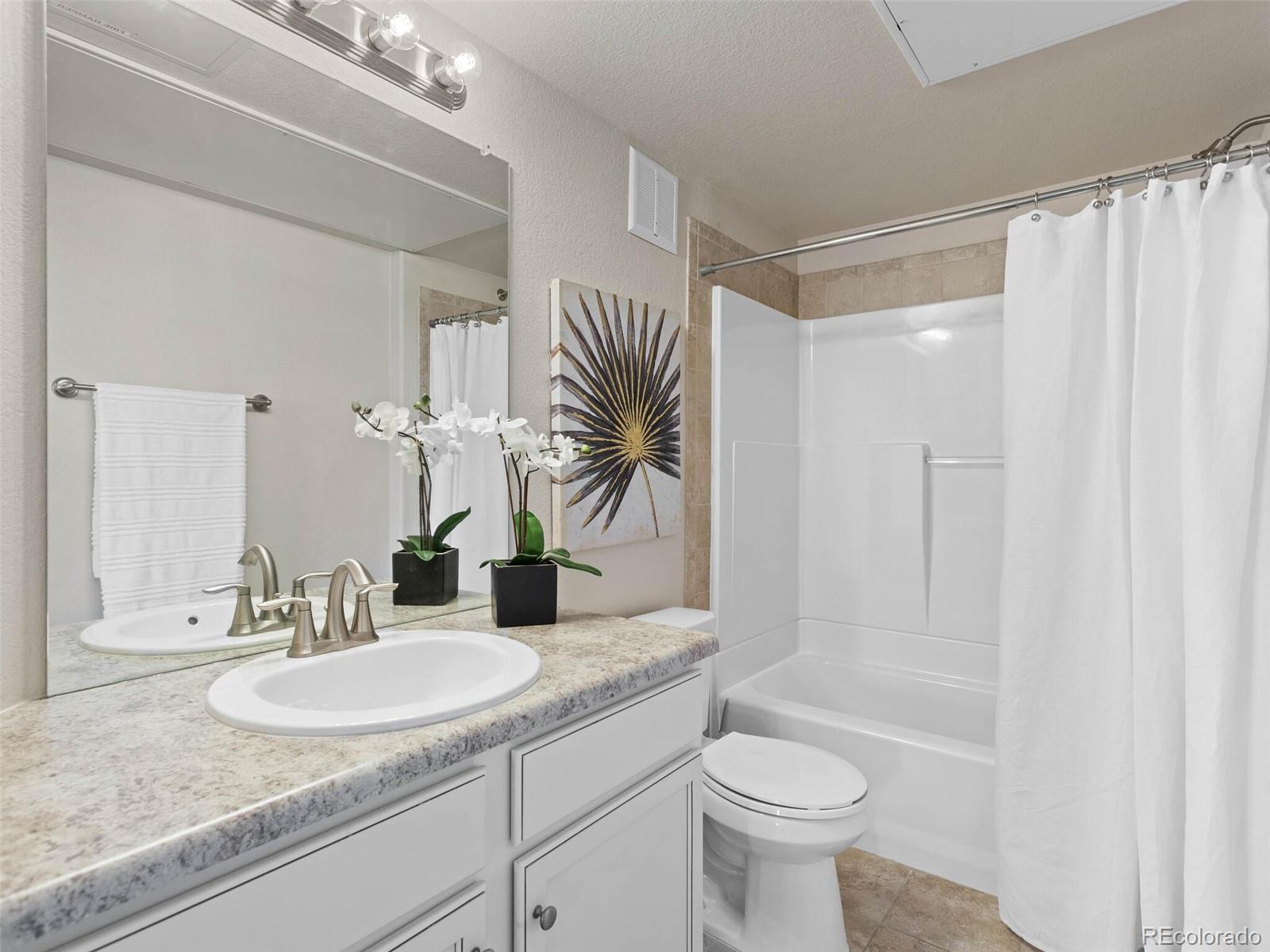 9258 Rockhurst Street, Unit 405 Highlands Ranch, CO 80129 - Photo 22 of 32 a bathroom with a granite countertop sink a toilet and shower