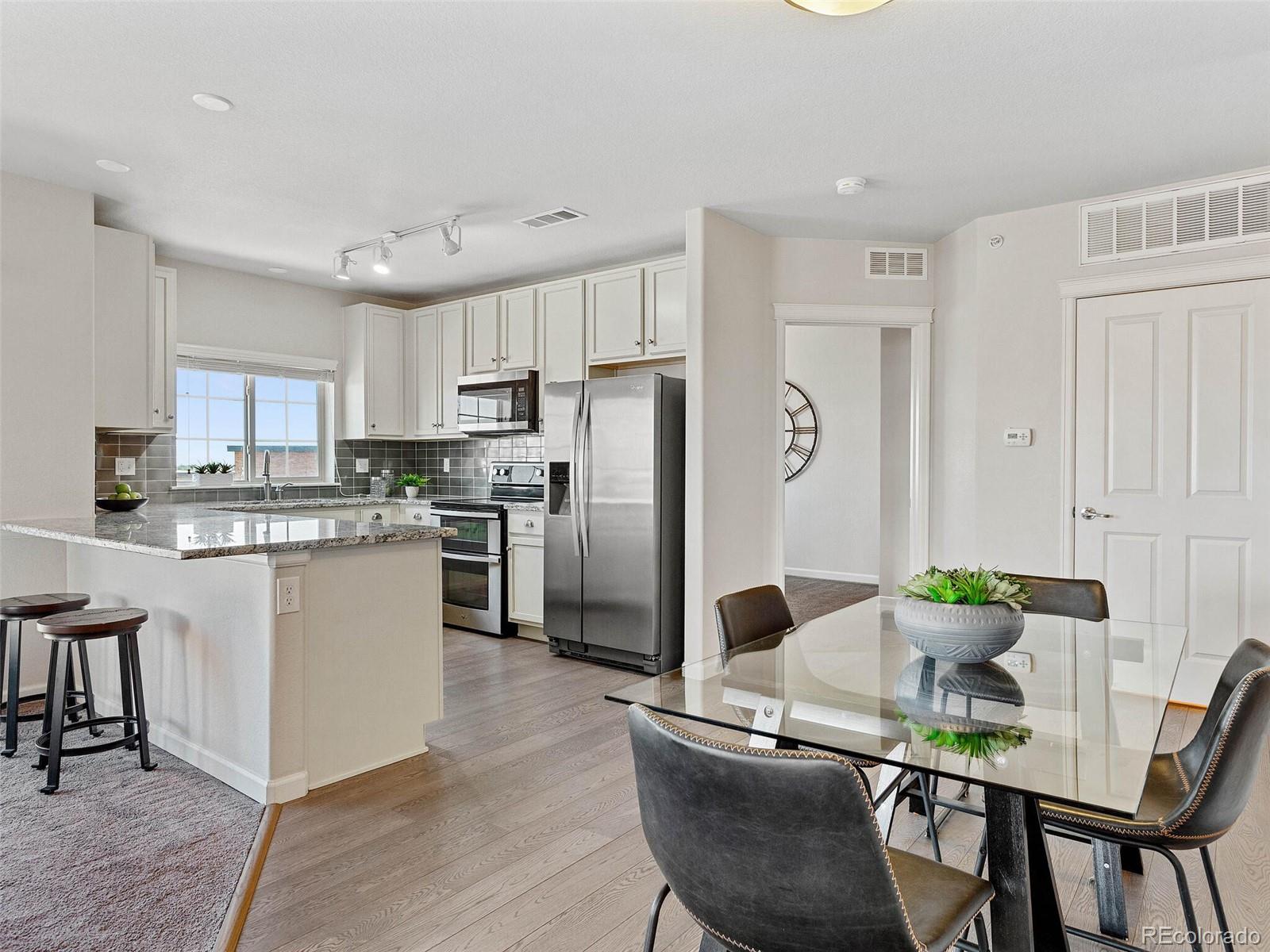 9258 Rockhurst Street, Unit 405 Highlands Ranch, CO 80129 - Photo 8 of 32 a kitchen with stainless steel appliances granite countertop a dining table chairs refrigerator and sink