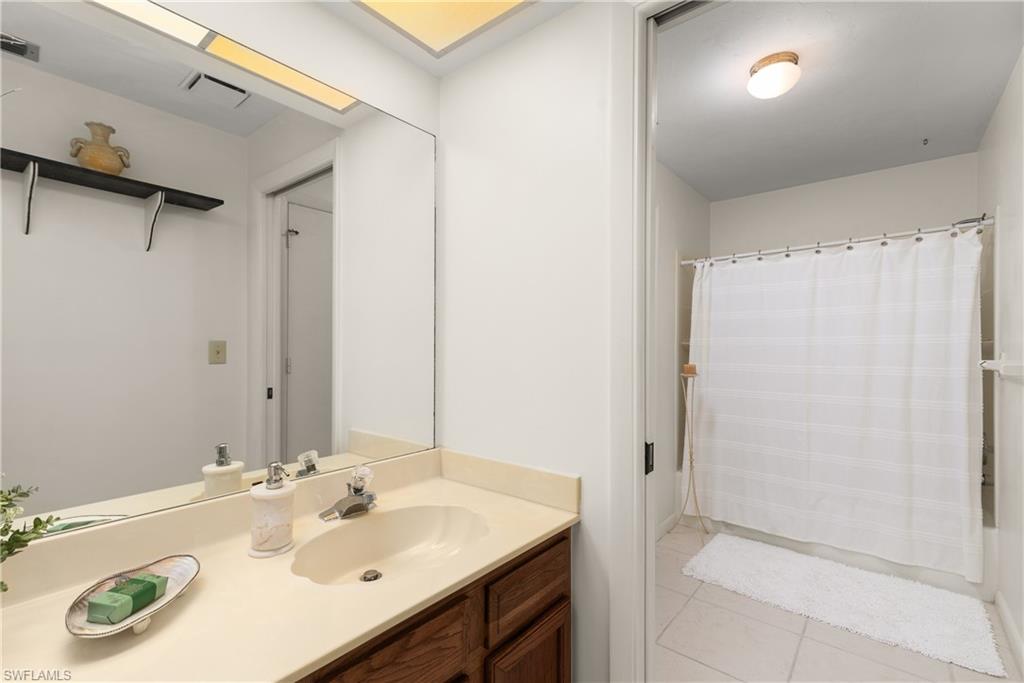 1833 Courtyard Way, Unit E204 Naples, FL 34112 - Photo 14 of 18 a bathroom with a sink a mirror and a shower