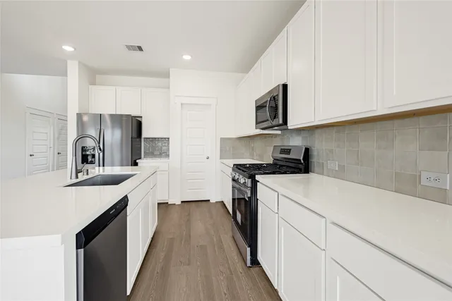 a kitchen with stainless steel appliances a sink stove refrigerator and cabinets