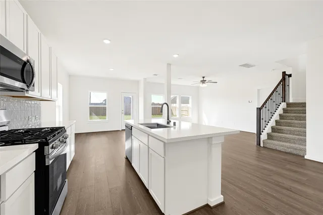 a kitchen with stainless steel appliances granite countertop a sink stove and wooden floor