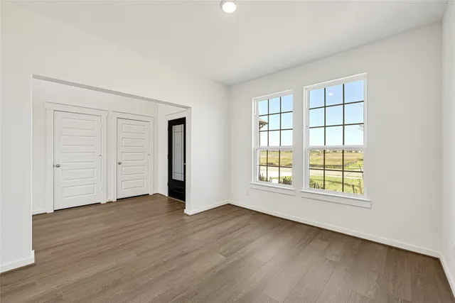 an empty room with wooden floor and windows