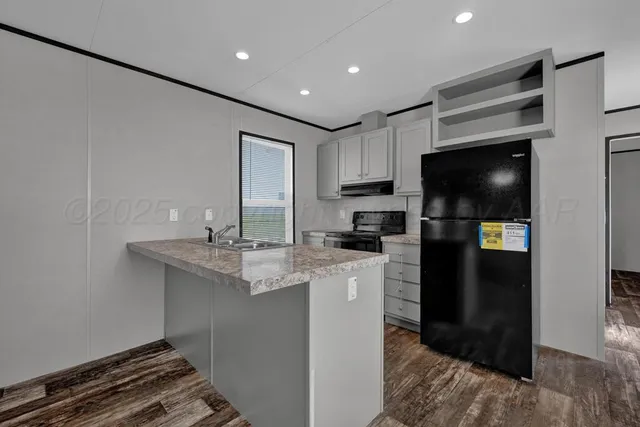 a kitchen with a sink stainless steel appliances a refrigerator and cabinets