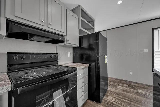 a kitchen with wooden cabinets stainless steel appliances and a wooden floor