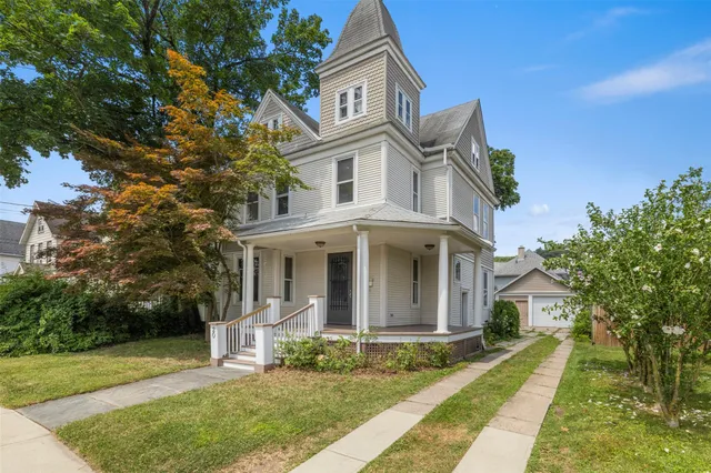 a view of a white house with large windows and a small yard