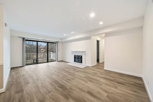an empty room with wooden floor fireplace and windows