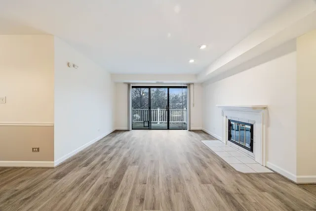 a view of empty room with wooden floor and fireplace