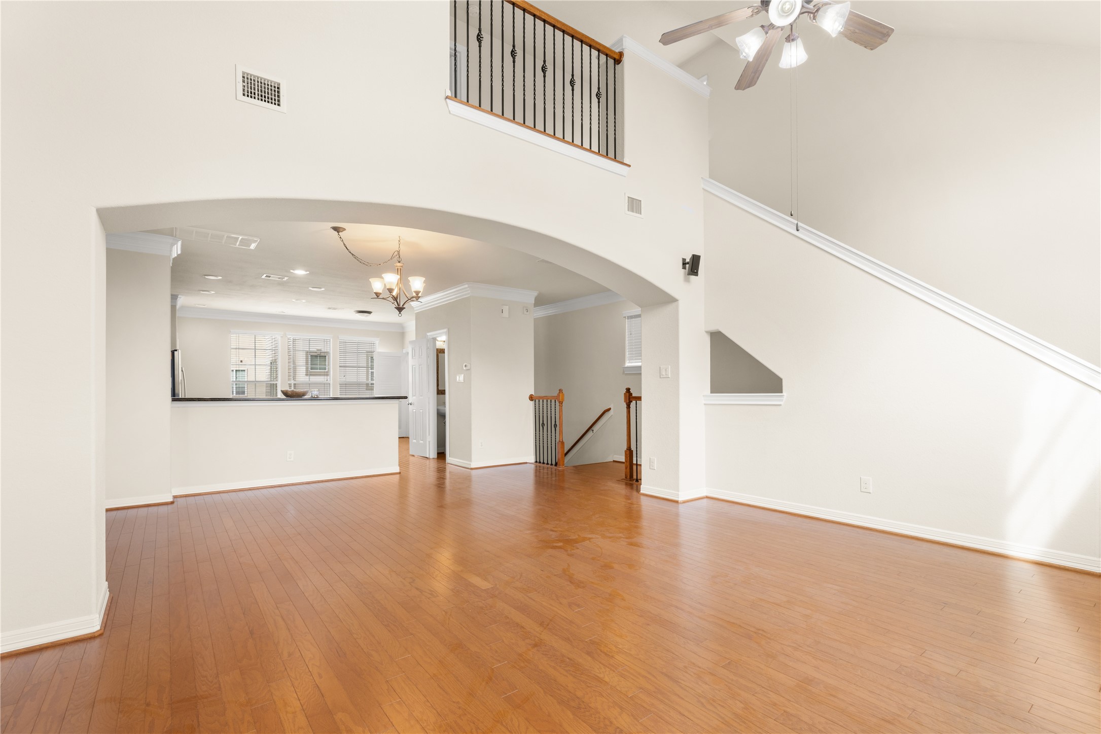 3334 Clearview Villa Way Houston, TX 77025 - Photo 7 of 35 This spacious, open-concept living area features hardwood floors, high ceilings, and abundant natural light. The room flows into a modern kitchen, visible through an elegant archway, and includes a staircase leading to an upper level Primary suite with sitting room.