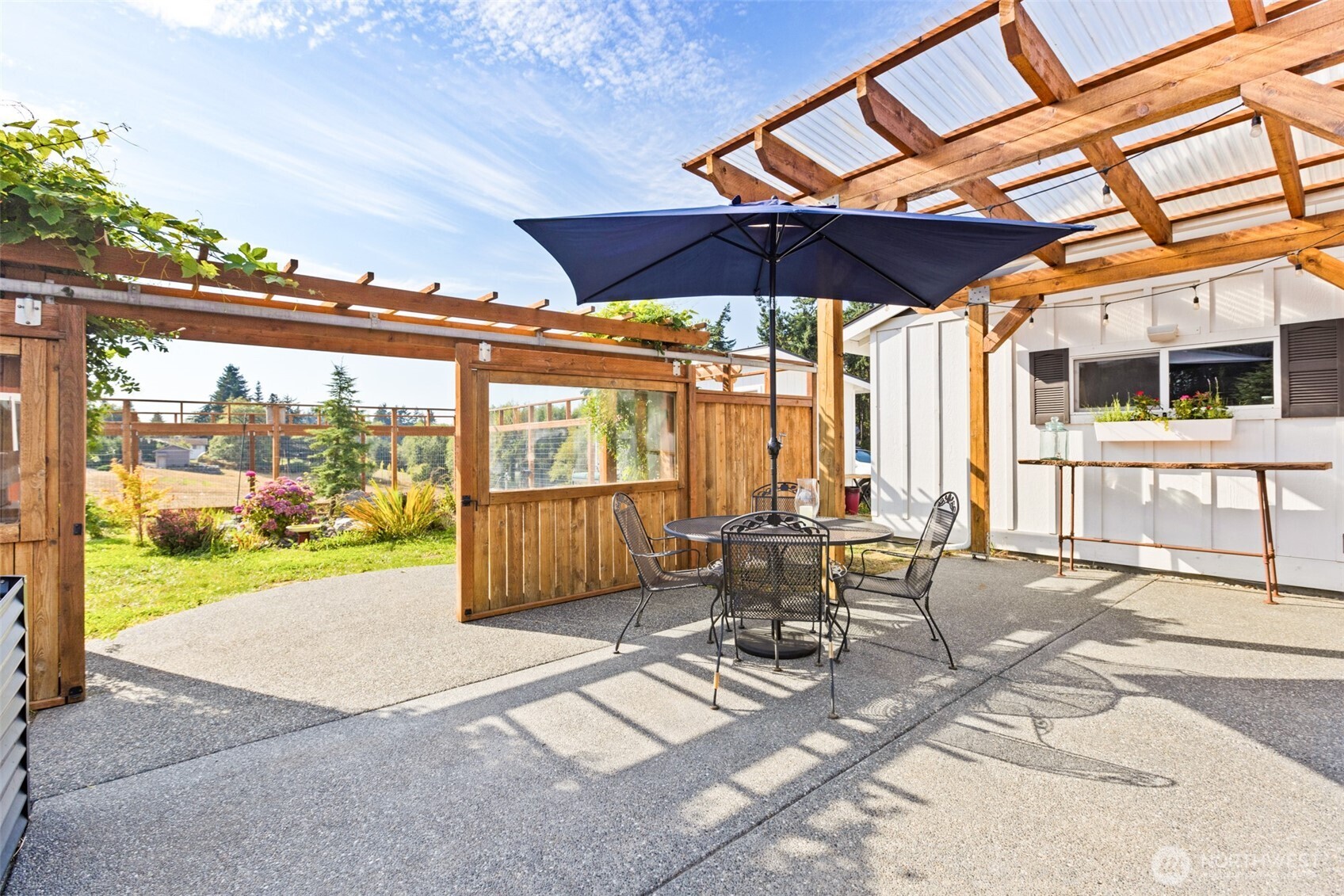 135 Edgington Drive Sequim, WA 98382 - Photo 28 of 40 a view of a patio with a table and chairs under an umbrella with a small yard