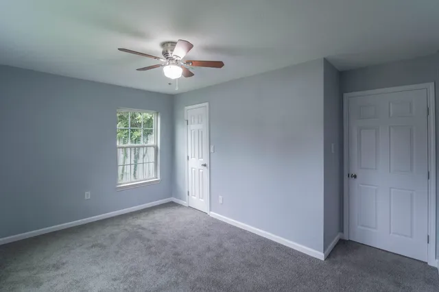 an empty room with windows and fan
