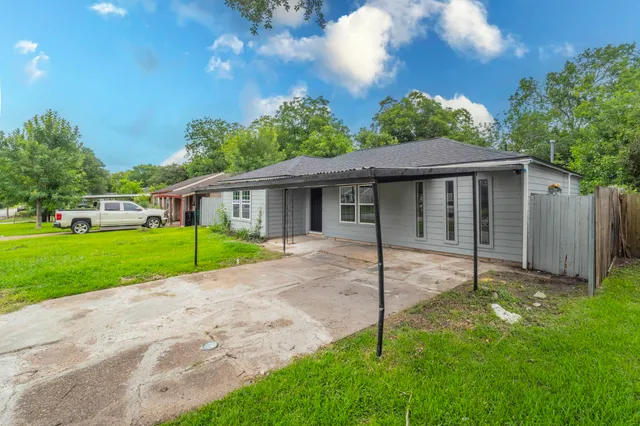 a view of a house with a big yard plants and large trees