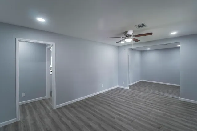 an empty room with wooden floor and a ceiling fan