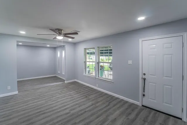 an empty room with wooden floor and windows