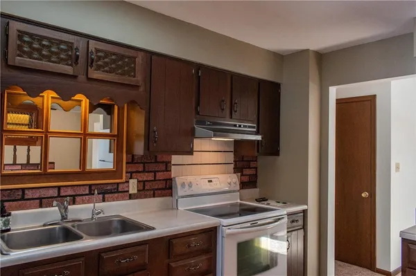a kitchen with stainless steel appliances granite countertop a sink and a stove next to a refrigerator with wooden cabinets