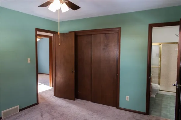 an empty room with closet and a chandelier fan