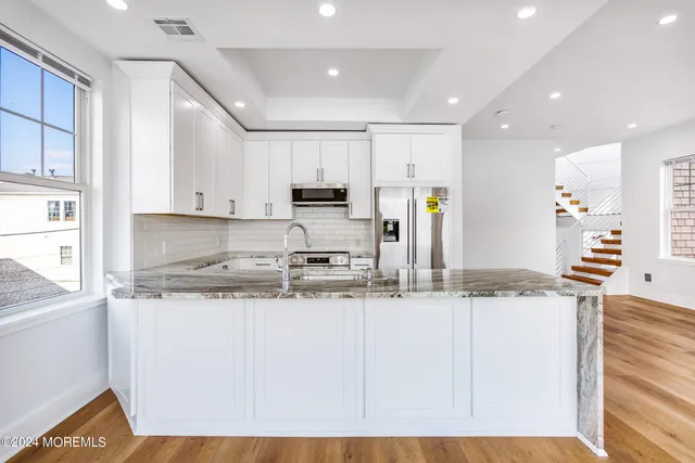 a kitchen with stainless steel appliances granite countertop a sink a stove and a refrigerator
