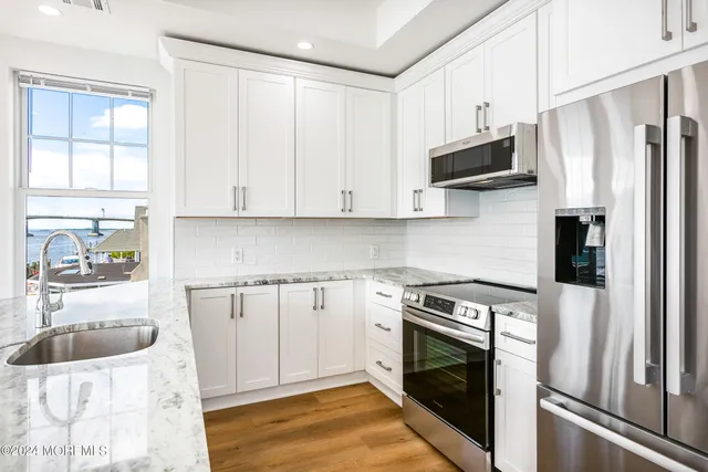 a kitchen with stainless steel appliances white cabinets and a refrigerator